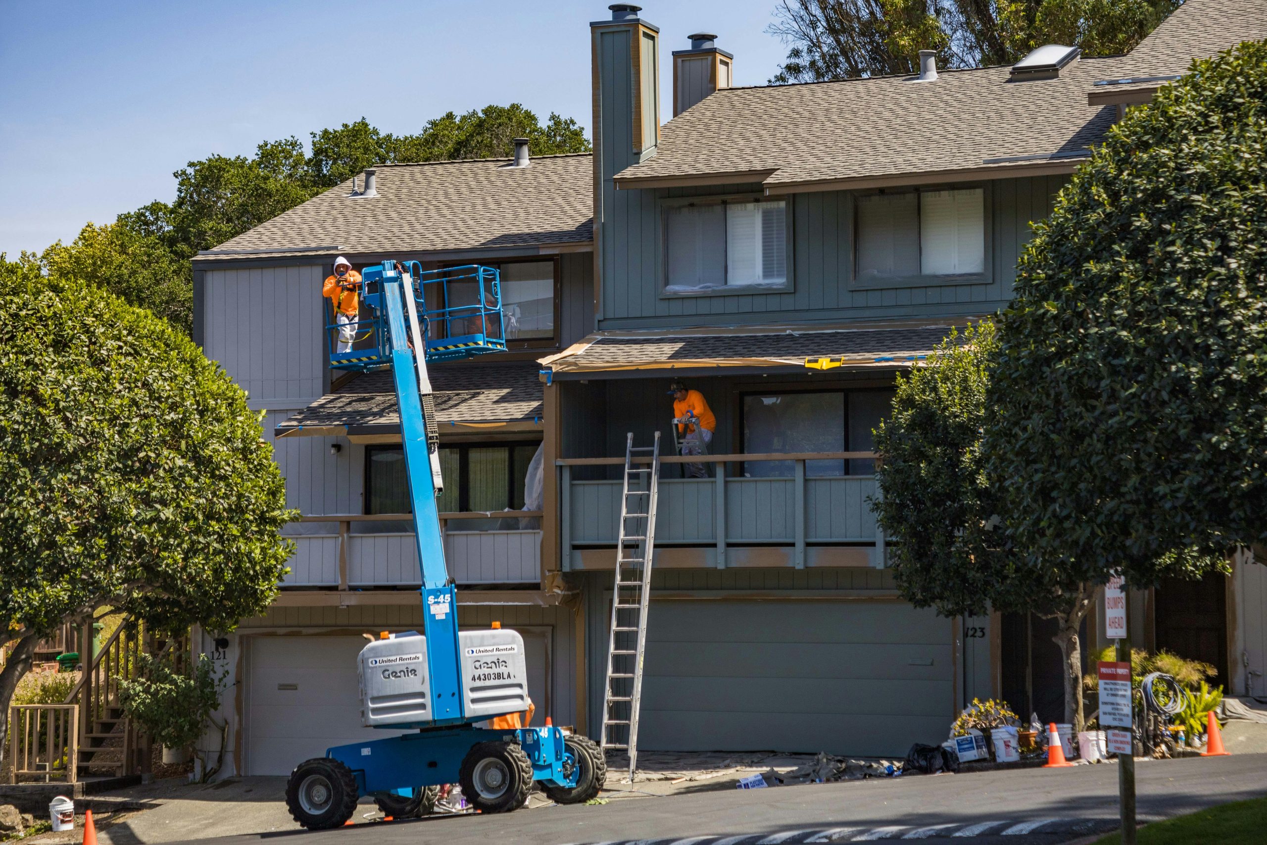 Home House being renovated with workers on a hydraulic lift in an urban area.