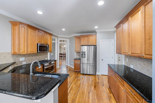 Home Spacious modern kitchen featuring granite countertops, wooden cabinets, and stainless steel appliances.