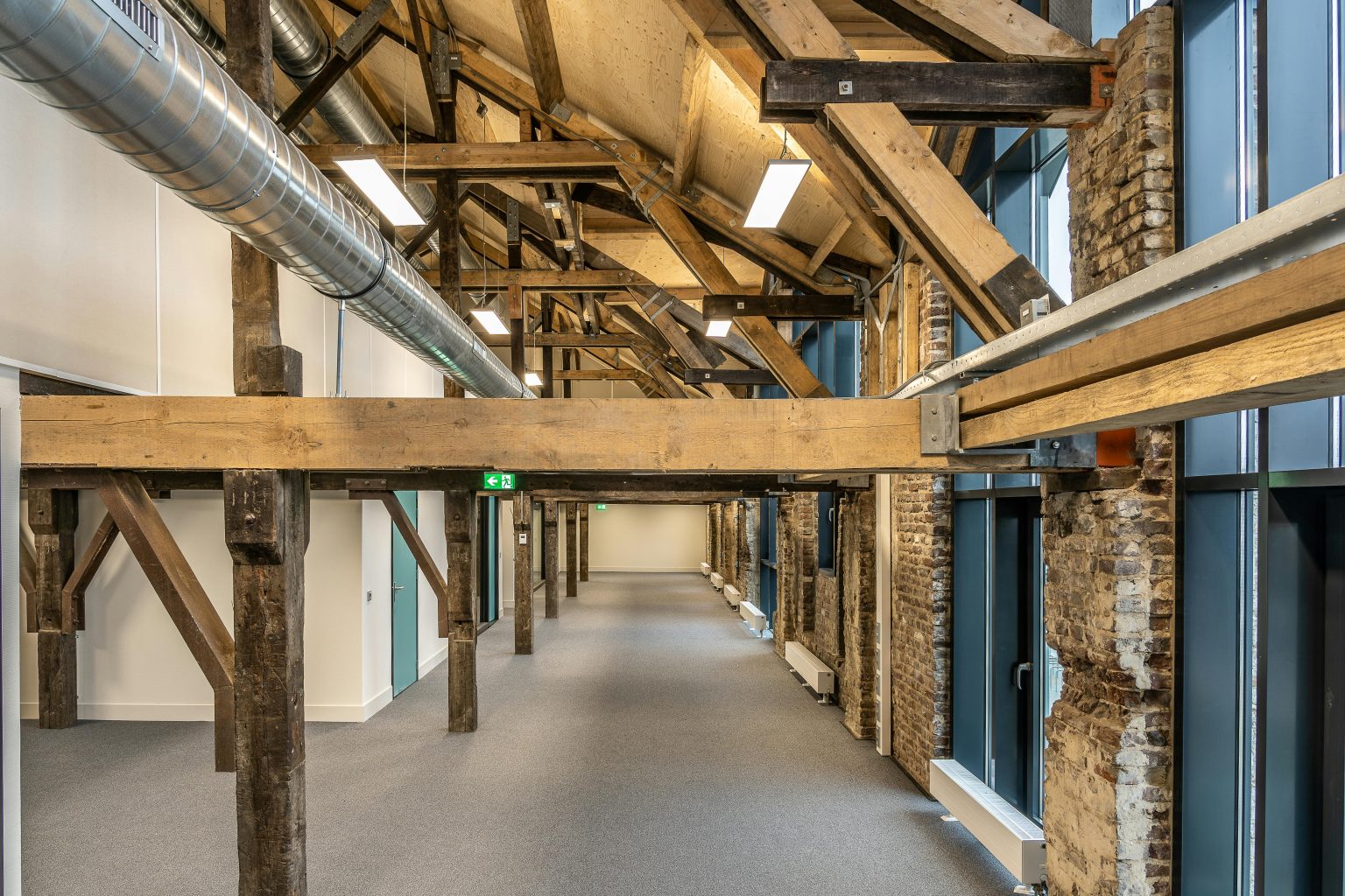 Home Spacious industrial loft with exposed wooden beams and ductwork, showcasing modern architecture.